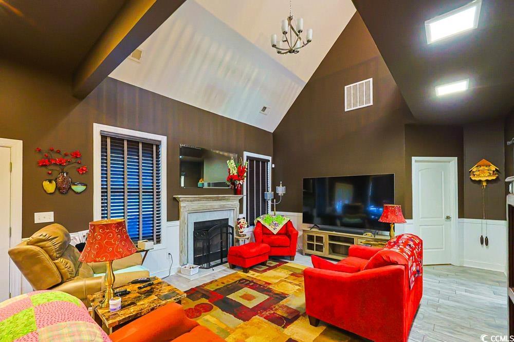 105 Rocko Drive Myrtle Beach, SC 29579 - Photo 10 of 38 Living room featuring wainscoting, a fireplace, high vaulted ceiling, a chandelier, and wood finished floors
