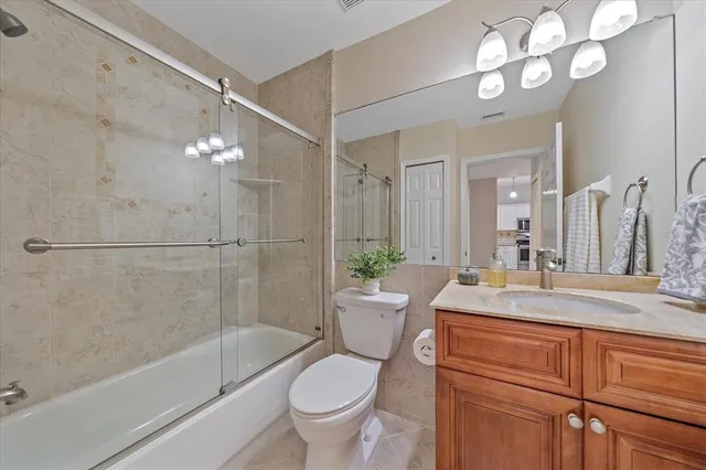 a bathroom with a granite countertop sink a toilet a mirror a bathtub and shower