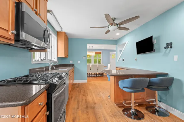 a kitchen with stainless steel appliances granite countertop a stove a sink dishwasher a dining table and chair with wooden floor