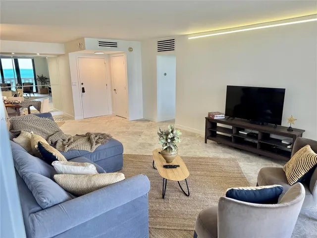 a living room with furniture and a dining table with kitchen view