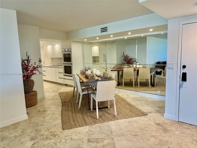 a large white kitchen with stainless steel appliances kitchen island granite countertop a stove a sink and a microwave