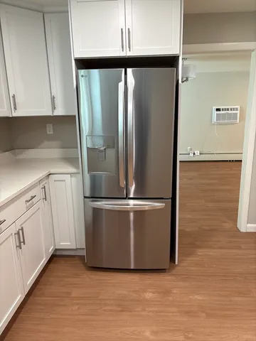a view of a refrigerator in kitchen with stainless steel appliances wooden floor