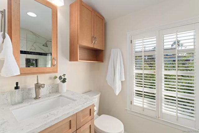 a bathroom with a granite countertop sink toilet and mirror