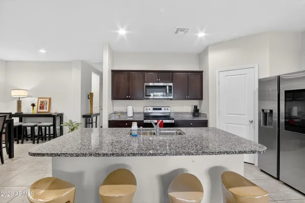 a open kitchen with stainless steel appliances granite countertop a sink dishwasher stove and refrigerator with wooden floor