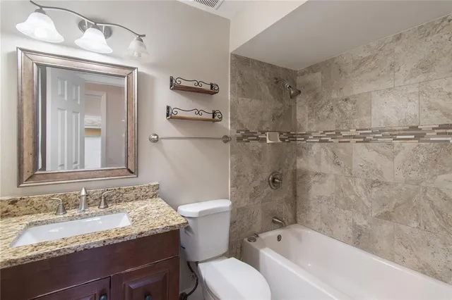 a bathroom with a granite countertop sink toilet and shower