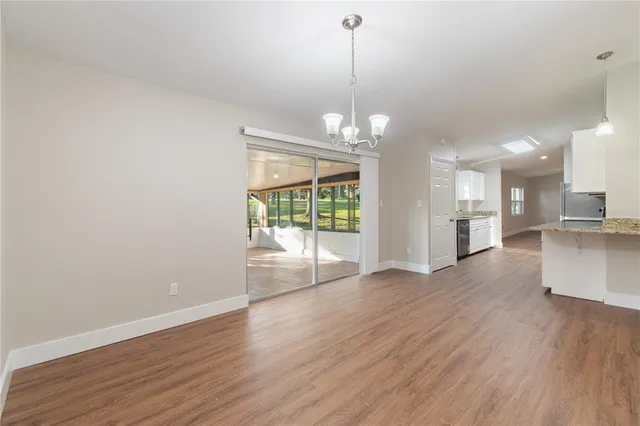 a view of a big room with wooden floor kitchen and windows