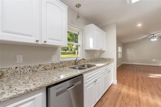 a kitchen with granite countertop white cabinets and a wooden floor