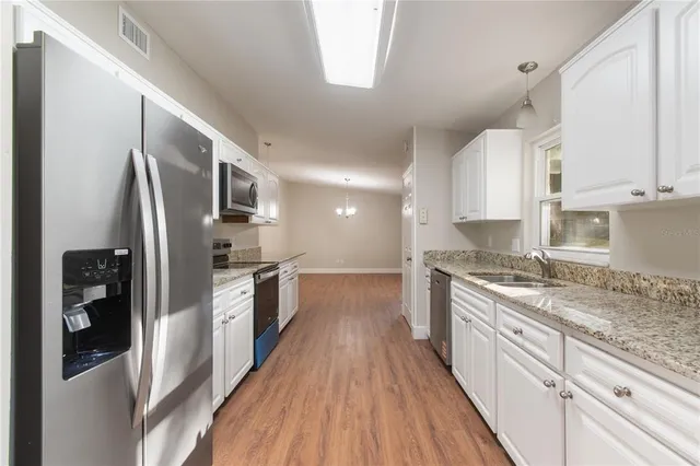 a kitchen with stainless steel appliances granite countertop a refrigerator a stove and a wooden floors