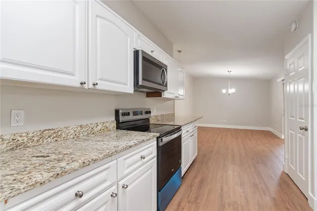 a kitchen with granite countertop cabinets stainless steel appliances and wooden floor
