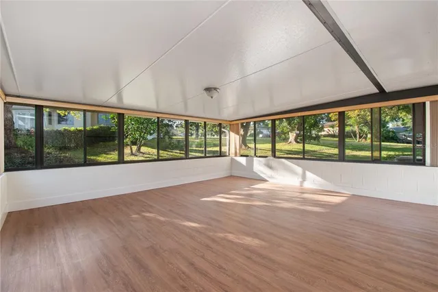 a view of an empty room with wooden floor and a floor to ceiling window