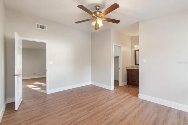 an empty room with wooden floor and a ceiling fan