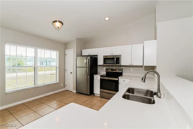 a kitchen with stainless steel appliances a sink a stove a refrigerator a window