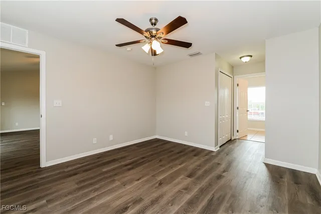 an empty room with wooden floor and a ceiling fan