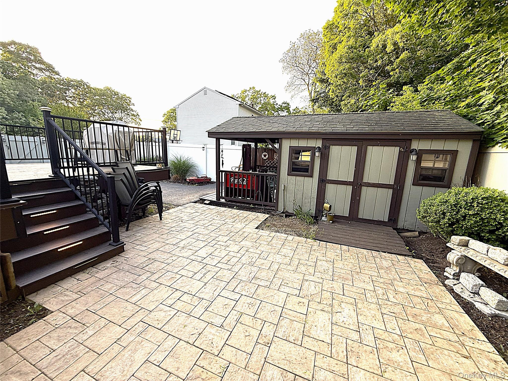 1 Heston Road Shirley, NY 11967 - Photo 27 of 32 Expansive patterned patio with a wood-finish deck featuring dark railings