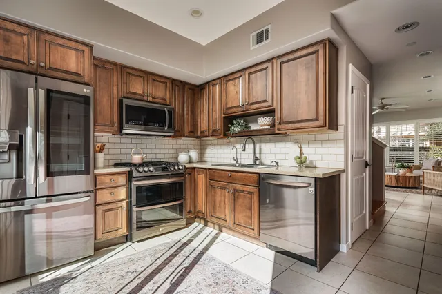 a kitchen with stainless steel appliances granite countertop a stove top oven a sink dishwasher a dining table and chairs with wooden floor