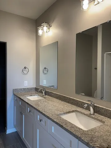 a bathroom with a granite countertop double sink and a mirror