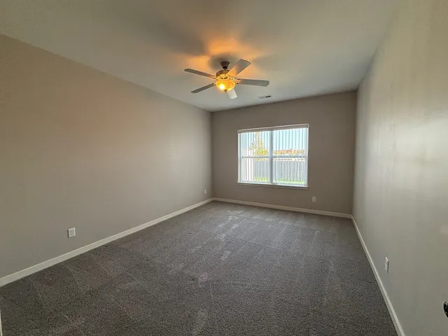 an empty room with a window and a fan