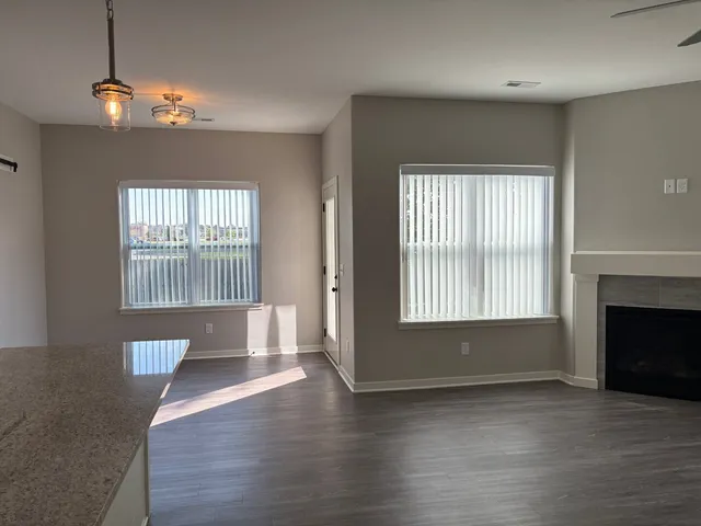 an empty room with wooden floor fireplace and windows