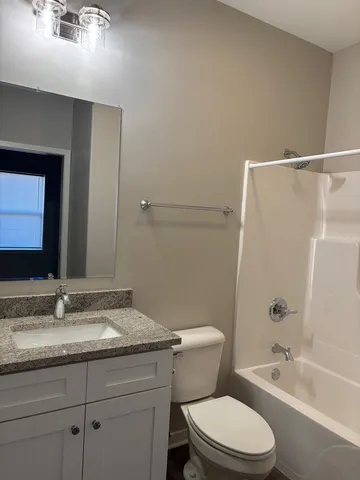 a bathroom with a granite countertop sink a toilet and shower