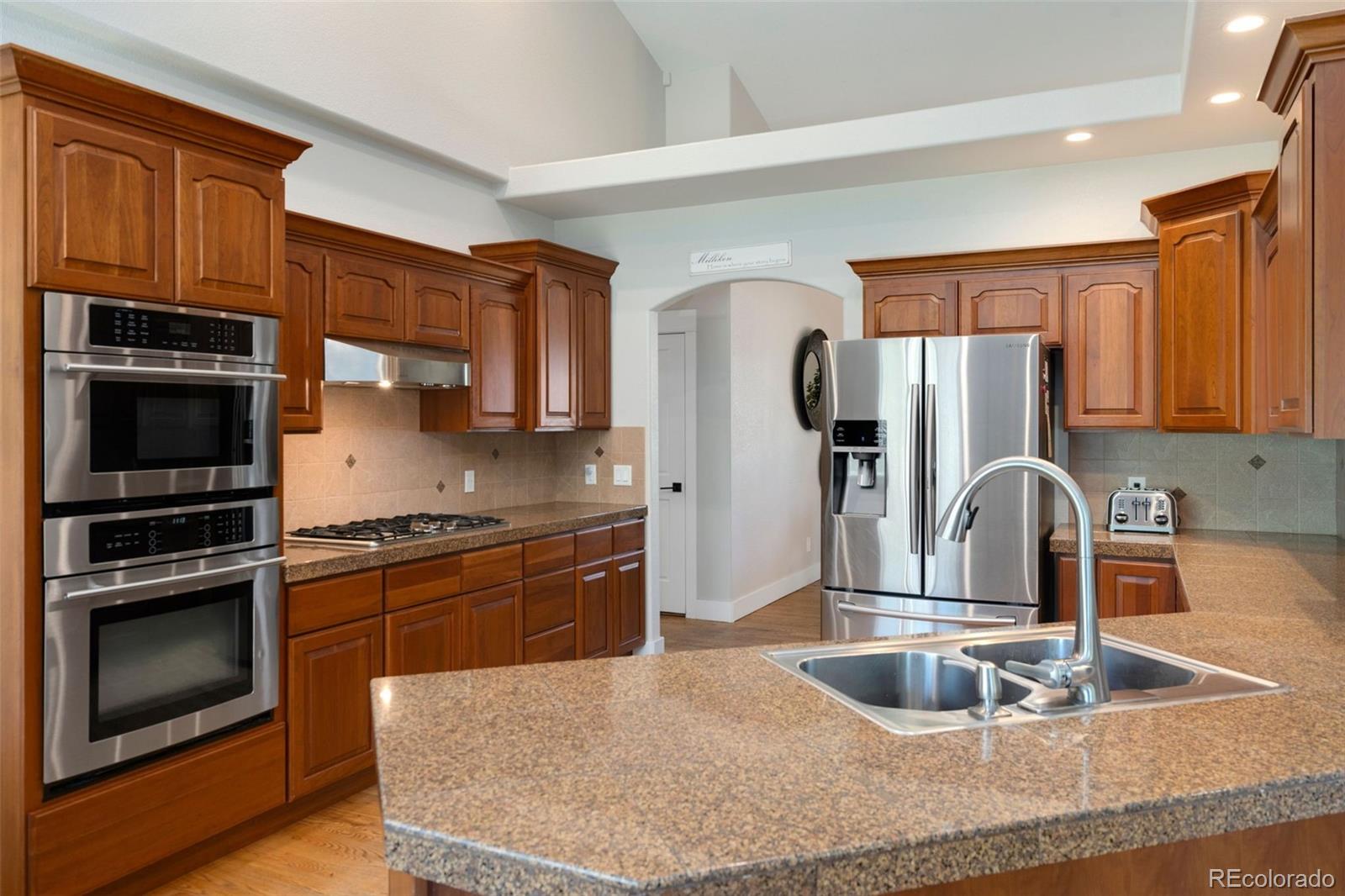 5475 Trade Wind Drive Windsor, CO 80528 - Photo 8 of 40 a kitchen with stainless steel appliances granite countertop a sink stove and refrigerator