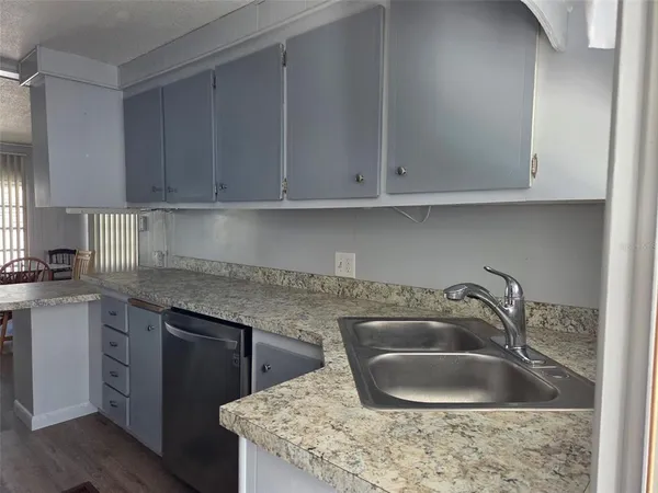 a kitchen with granite countertop a sink dishwasher a stove and cabinets