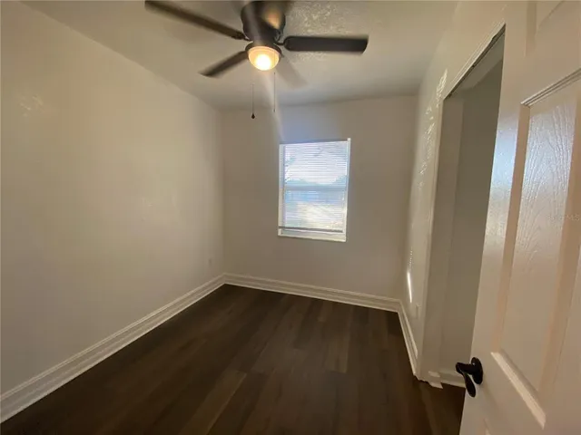 an empty room with wooden floor and fan