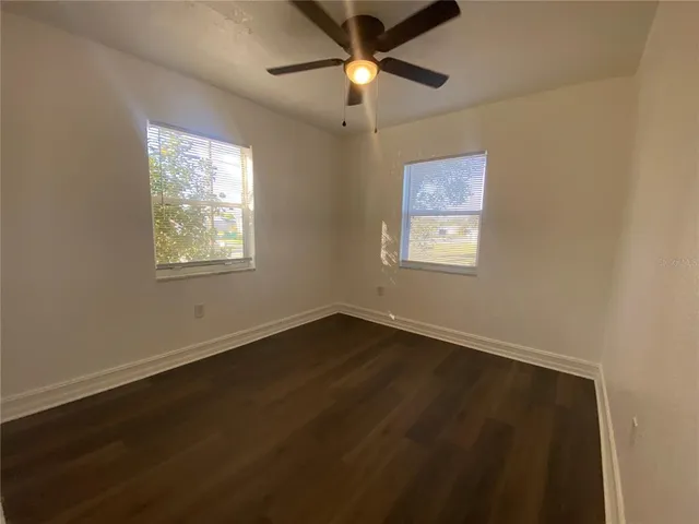 a view of an empty room with window and wooden floor