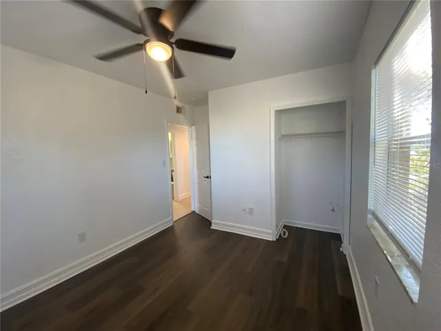 an empty room with wooden floor cabinet and windows