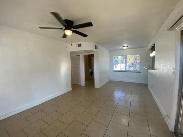 a view of an empty room and window and ceiling fan