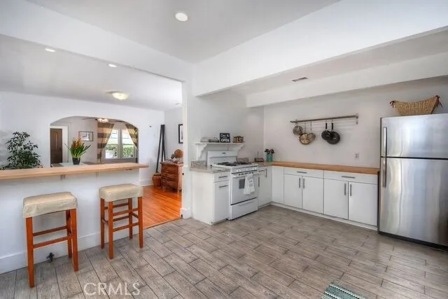 a large white kitchen with granite countertop a refrigerator and a stove top oven
