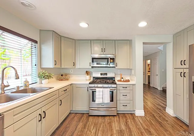 a kitchen with stainless steel appliances a white stove top oven sink and cabinets