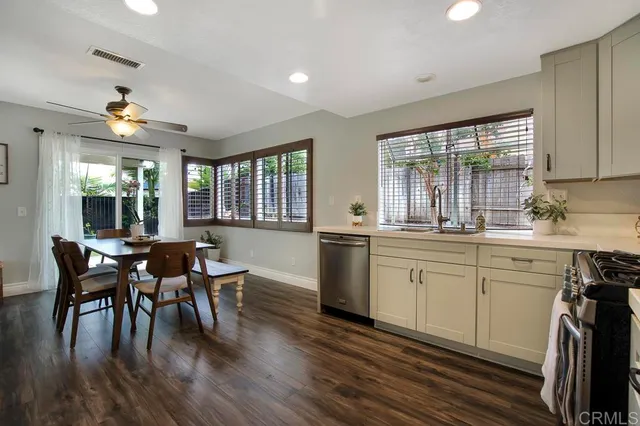 a kitchen with stainless steel appliances granite countertop a stove top oven a sink dishwasher a dining table and chairs with wooden floor