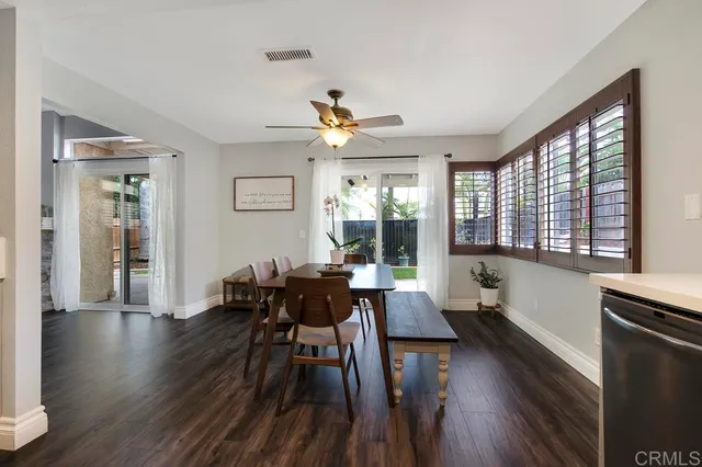 a dining room with wooden floor and large windows