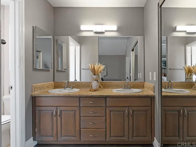 a bathroom with a granite countertop double vanity sink and mirror