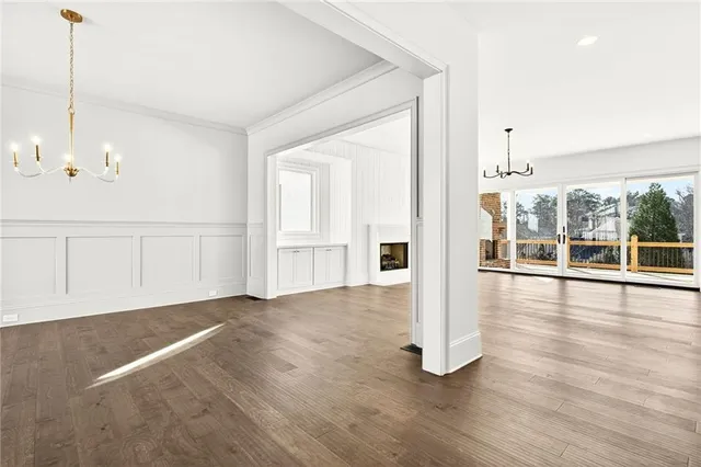 a view of an empty room with wooden floor and windows