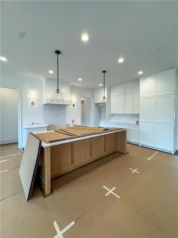 a large kitchen with a large counter top a sink stainless steel appliances and cabinets