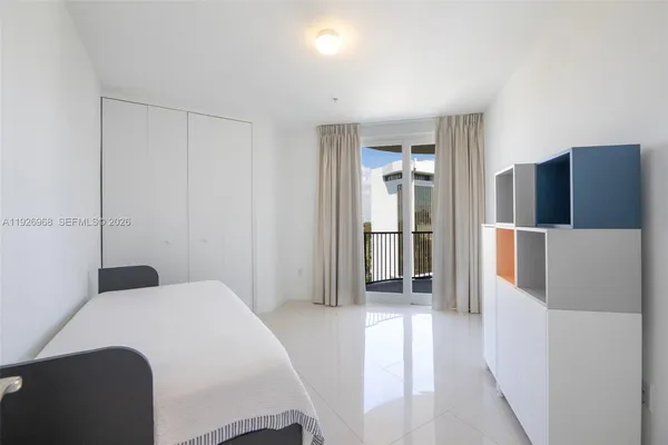 a bedroom with a bed and a refrigerator