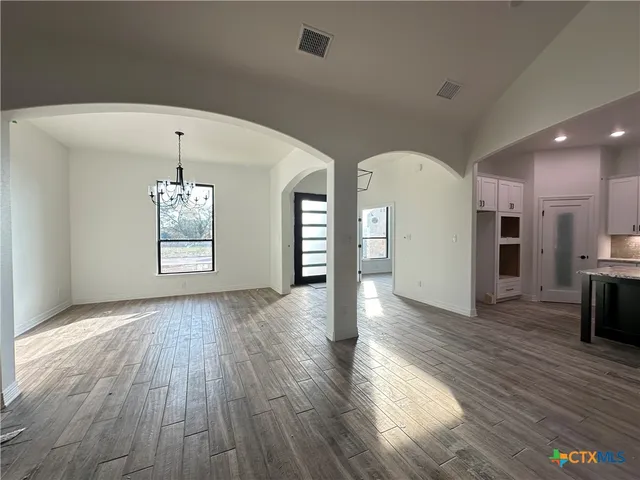 a large kitchen with stainless steel appliances kitchen island a refrigerator and a wooden floor