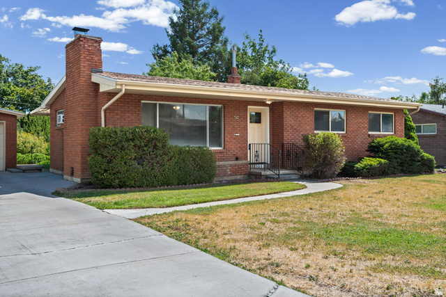 542 East 3400th Street North Provo, UT 84604 - Photo 1 of 39 Brick ranch-style residence featuring a prominent brick chimney, an attached garage, a concrete driveway, a curved concrete walkway, and established foundation plantings