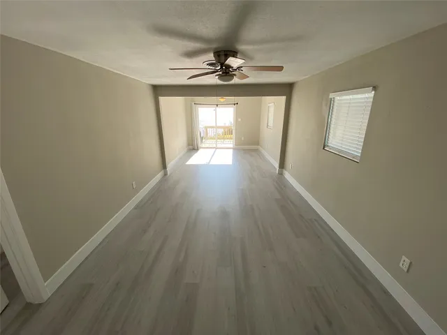 a view of a room with wooden floor fan and windows