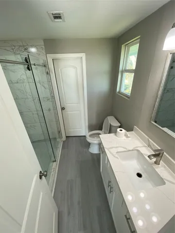 a spacious bathroom with a double vanity sink a toilet and a mirror