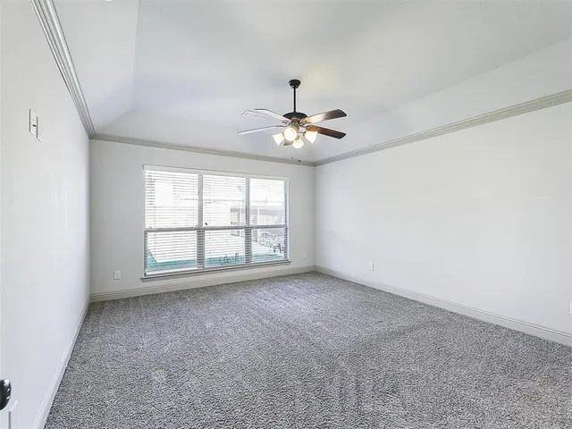 an empty room with chandelier fan and windows