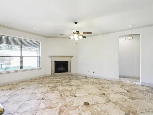 en empty room with a fireplace and ceiling fan