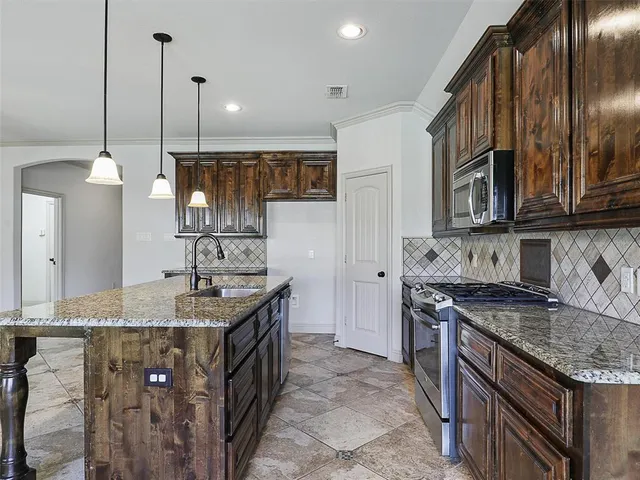 a kitchen with stainless steel appliances granite countertop a sink a stove and a wooden floors