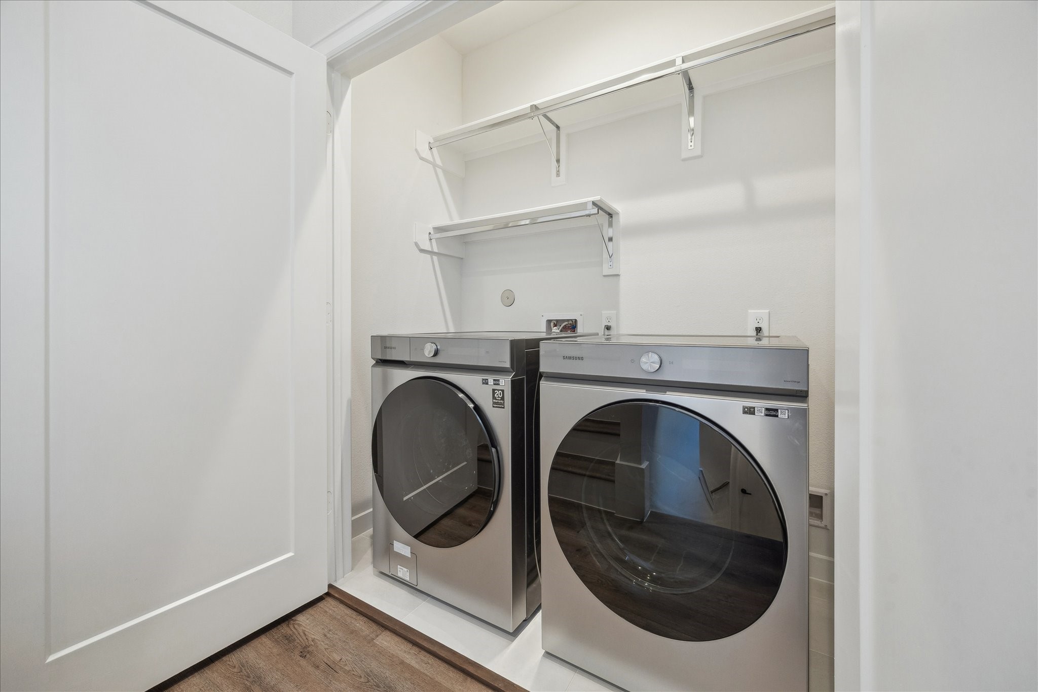 1603 Patterson Street, Unit E Houston, TX 77007 - Photo 22 of 32 This photo showcases a compact laundry area featuring modern front-loading washer and dryer units with shelving above for storage. The space has a clean, minimalistic design.