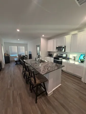 a kitchen with stainless steel appliances granite countertop a lot of counter top space and a wooden floor