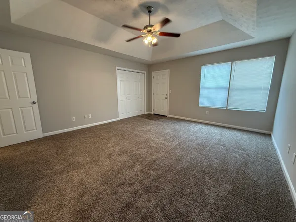 an empty room with chandelier fan and closet area