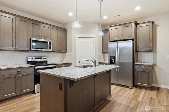 a kitchen with kitchen island granite countertop stainless steel appliances cabinets a sink and a center island