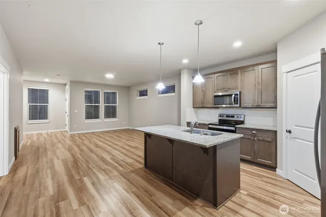 a kitchen with stainless steel appliances a stove top oven a sink dishwasher a refrigerator and white cabinets with wooden floor