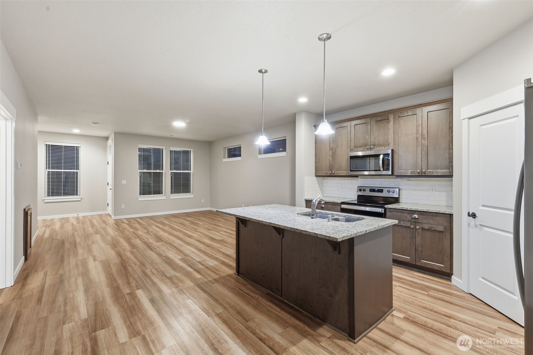7110 South 13th Street Ridgefield, WA 98642 - Photo 5 of 28 a kitchen with stainless steel appliances a stove top oven a sink dishwasher a refrigerator and white cabinets with wooden floor